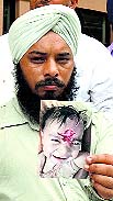Hardeep Singh shows a picture of his three-month-old son who was attacked by a monkey at Mangli Tanda village. 