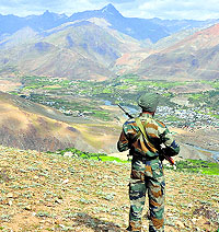 An Army jawan near Dras with Tiger Hill in the backdrop