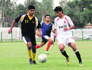 Players vie for the ball during a match in the District Football League at Pavilion Ground in Dehradun on Thursday.