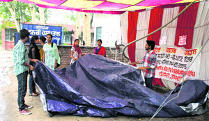 Striking students try to save their tent from the rain on the GADVASU campus in Ludhiana.