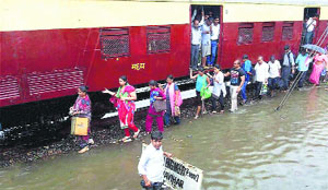 Commuters alight from a train which was stopped due to flooded tracks following downpour in Mumbai.