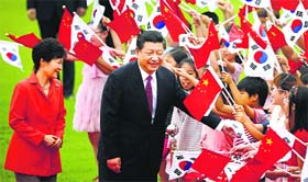 Chinese President Xi Jinping (C) and South Korean President Park Geun-hye (L) greet children in Seoul on Thursday.