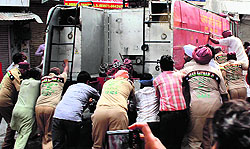 Volunteers of Dera Sacha Sauda and shopkeepers push a fire tender in Bathinda on Friday