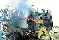 A policeman tries to put out fire from a burning truck at Aaripal Tral in Pulwama district on Saturday
