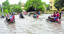 People drive through a waterlogged road after heavy rain in Patna on Saturday. PTI