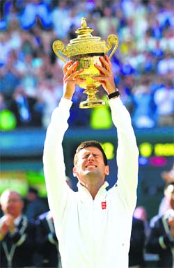 Novak Djokovic reacts while holding the winners trophy in the Centre Court.