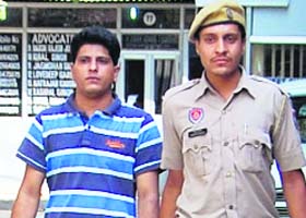 Jail inmate Dheeraj Batra being taken away by the police from the Mohali District Courts on Monday