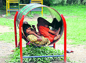A girl rests inside a playing stand to get shade from the sun at Gandhi Park in Dehradun on Monday.