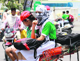 A student tries to save herself from the scorching heat by coverning her face while returning home from the school in Bathinda on Tuesday.