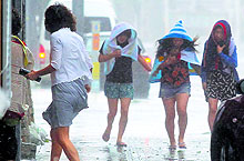 Women walk in strong winds caused by typhoon Neoguri in Naha, on Japan's southern island of Okinawa on Tuesday
