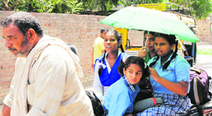 Schoolchildren use an umbrella to protect themselves from the sun on a hot summer afternoon in Amritsar on Wednesday.