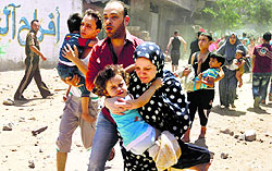 Palestinians run following an Israeli air strike on a house in Gaza city on Wednesday