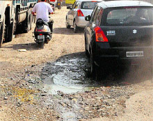 Vehicles navigate through a potholed road