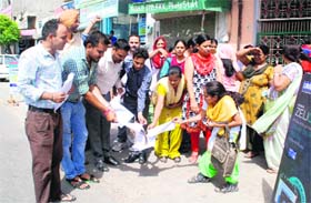 Members of the Unaided Staff (aided school) Front Punjab burn a copy of the notification in Bathinda on Thursday