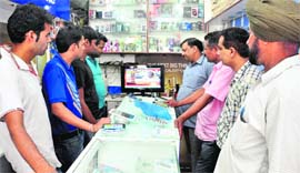 Customers and shopkeepers watch the Budget speech at a shop.