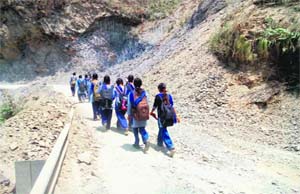 Schoolchildren pass through the road being widened near Nainbagh by the National Highways Authority of India on Thursday.