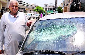 Kuldeep Kumar Singla points at the smashed windshield of his Maruti Zen car on Friday.