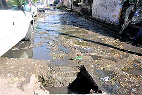 A road with potholes and drain water at Bahu Plaza in Jammu.