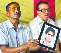 Jagdish Chand shows a picture of his son, who was allegedly kidnapped and killed in 2012, during a press conference in Ludhiana on Friday. 