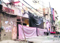 The front portion of the building is covered with sheets as construction activity continues in an unlawful manner on a plot at Old Sabzi Mandi Chowk in Ludhiana.