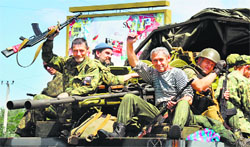 Pro-Russian militants sitting atop a truck wave as they drive past a checkpoint near Donetsk on Friday. AFP
