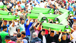 Bosnian Muslims carry some of the 175 coffins of newly identified victims from the 1995 Srebrenica massacre, during a mass funeral at Potocari Memorial Center, near Srebrenica on Friday. Reuters