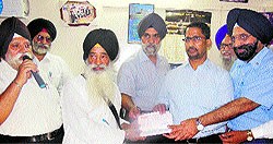 Local Body Minister Anil Joshi hands over a cheque of Rs 1 lakh to members of Bhai Ghanaiya Ji Mission Society in Amritsar on Saturday