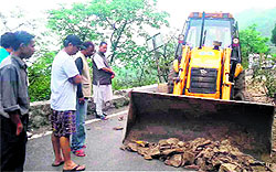 Workers remove the debris from the Mussoorie-Dehradun road near Kholokhet in Mussoorie on Sunday as Mussoorie MLA Ganesh Joshi looks on