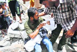 Father of four-year-old Palestinian boy Muayed al-Araj, who was killed in an Israeli air strike, with his body as he sits on the rubble of his house in Gaza on Sunday.