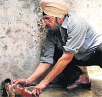A resident, Jagdish Singh, collects water full of mud from a water supply line in the Bagh Ramanand area in Amritsar. 