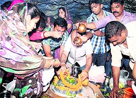 Devotees pray at Tapkeshwar Mahadev Temple in Dehradun on Monday.
