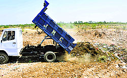 A Municipal Corporation tipper unloads solid waste at a dumping site in Jammu