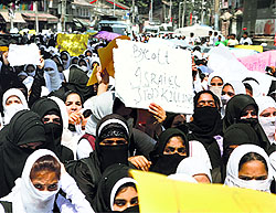 College students hold placards and shout anti-Israeli slogans during a protest against Israeli military operations in Gaza, in Srinagar on Monday