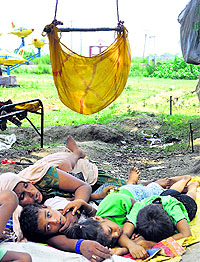 A woman takes a nap with her children in a hot afternoon at Bishnah on the outskirts of Jammu