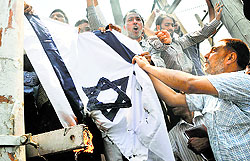 Members of the Jammu and Kashmir Employees Joint Consultative Committee burn the Israel flag during a protest against Israeli military operations in Gaza, in Srinagar on Monday