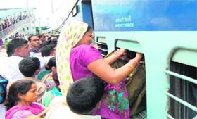 A woman tries to board a train via an emergency window at Haridwar railway station on Tuesday