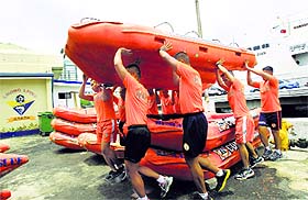 Members of the Philippine Coast Guard carry a rescue boat as they prepare for Typhoon Rammasun in Manila on Tuesday.