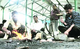 Craftmen make bronze items during an exhibition at the Anthropology Survey of India in Dehradun on Wednesday