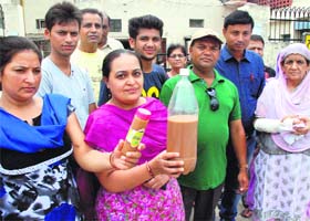 Residents show muddy water outside the MC office in Dera Bassi on Thursday