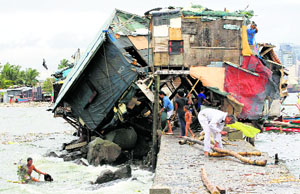 People near a damaged house after strong winds brought by Typhoon Rammasun battered the Baseco compound in Manila on Thursday.
