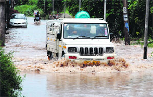 A motorist makes way through a flooded road near Sector 19, Panchkula, on Friday. 