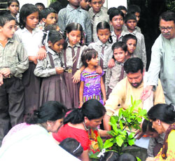 Ganga Action Family activists plant saplings with the help of students of Government Primary School, Laxman Jhula in Pauri on Friday.