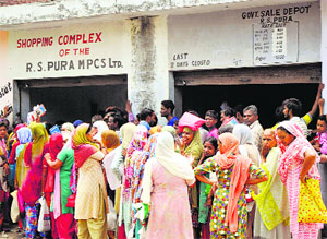 People await their turn at a ration depot in the RS Pura area of Jammu on Friday.