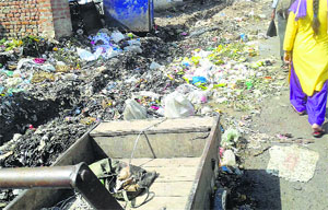 People walk past a garbage-strewn street in Udhampur