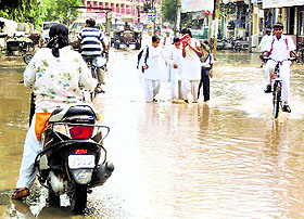 Schoolchildren and commuters make way through a flooded road in Jagraon. 