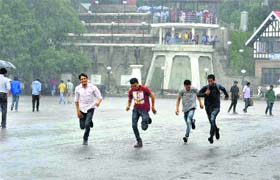 Boys run for shelter as it rains in Shimla on Saturday