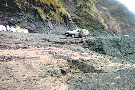 A vehicle crosses a landslide-prone stretch at Dhatri village near Dharamsala on Sunday