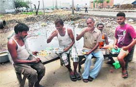 People have their meals at a roadside vend close to a pond of stagnant water in Jalandhar