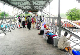 Passengers sit on the railway overbridge at the railway station due to poor seating arrangements in Bathinda.