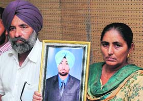 Balwinder Singh and Kamaljit Kaur, parents of deceased Harjeet Singh Joshan, show his photo at a press conference in Chandigarh on Monday.